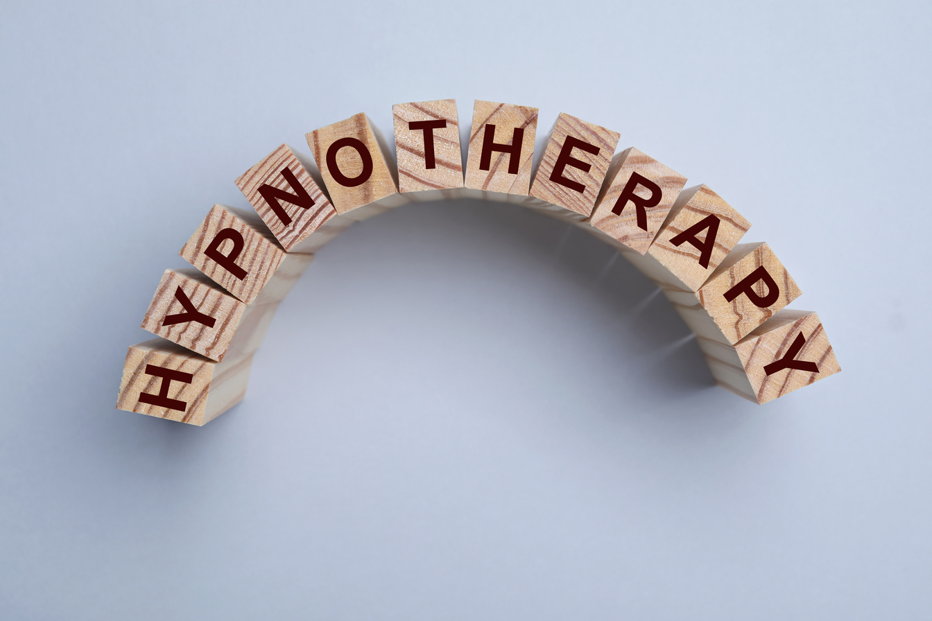 Wooden Blocks with Word HYPNOTHERAPY on Light Background, Flat L